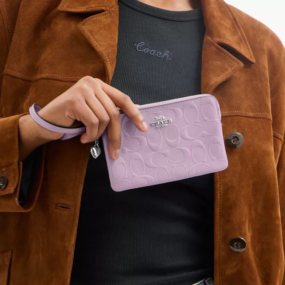 Handgelenktasche mit Reißverschluss an der Ecke aus Signature-Leder mit Herz-Anhänger